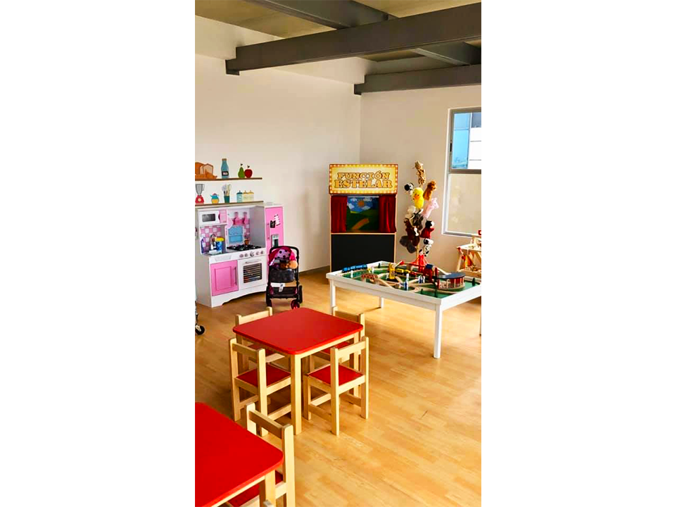 Una sala con mesas y sillas y una cocina al fondo.