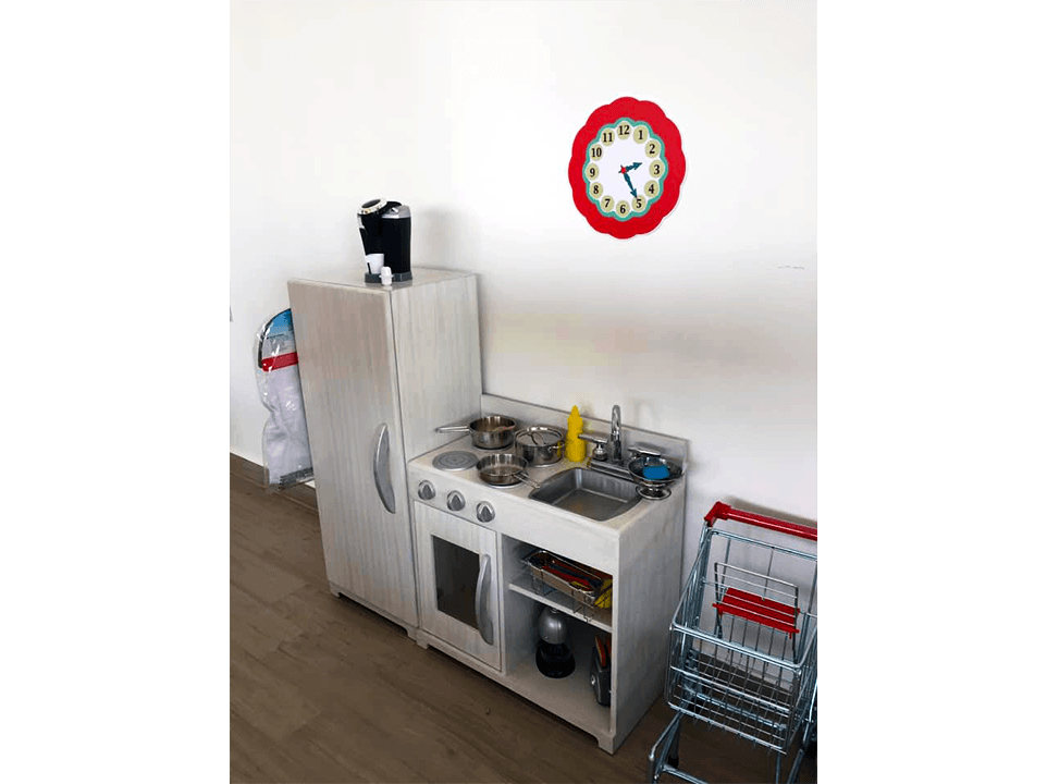 Una cocina con refrigerador, fregadero, estufa y un reloj en la pared.