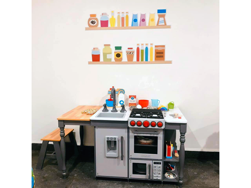 Una cocina de juguete con estufa, fregadero y microondas.