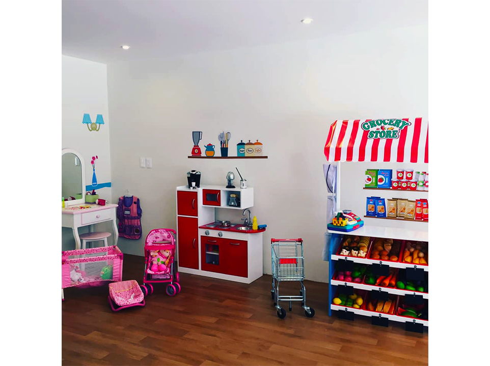 Una habitación infantil con cocina de juegos, cuna y carrito de compras.