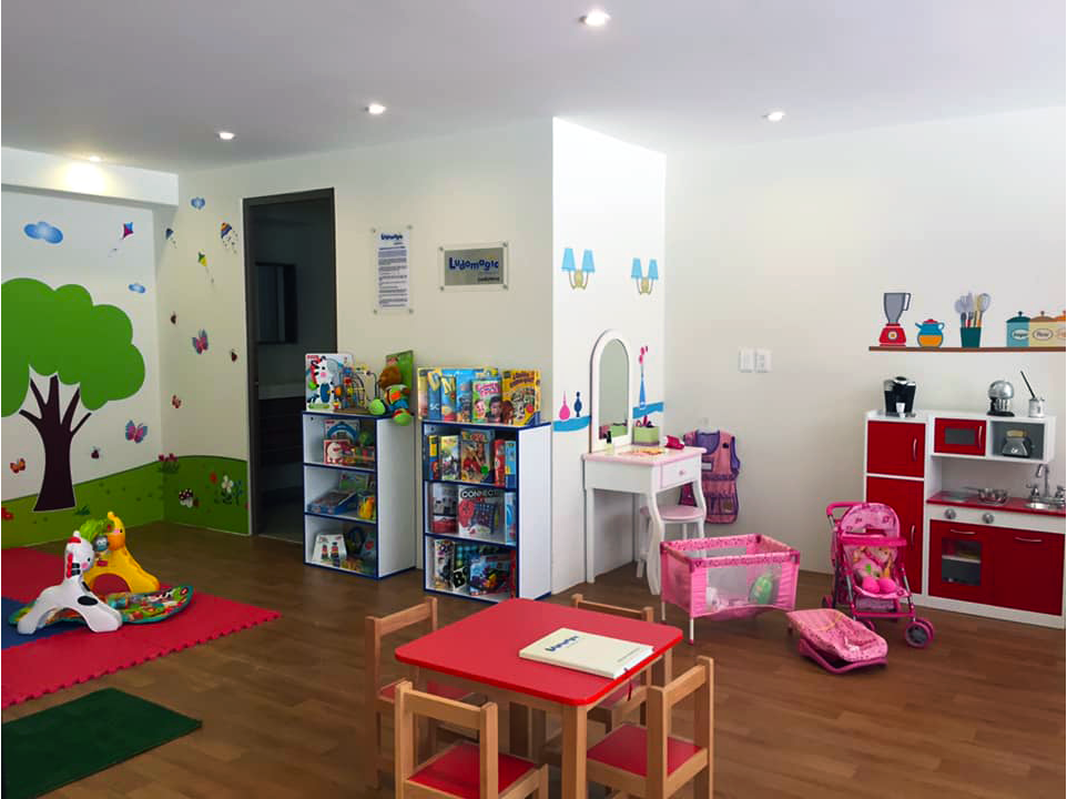 Una sala de juegos para niños con mesas, sillas y un cochecito.