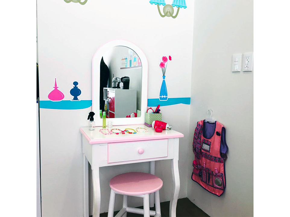 Un tocador infantil con un espejo y un taburete en una habitación.