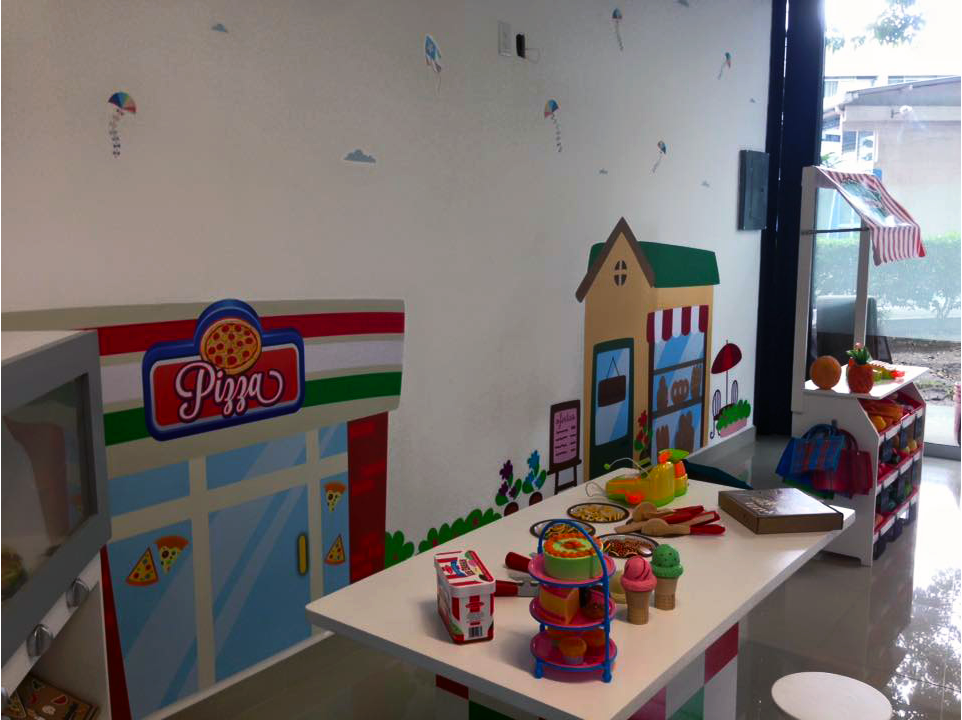 Una zona de juegos para niños con una pizzería en la pared