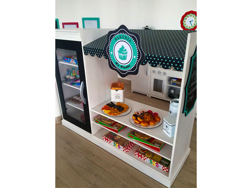 Una panadería de juguete con nevera y un reloj en la pared.