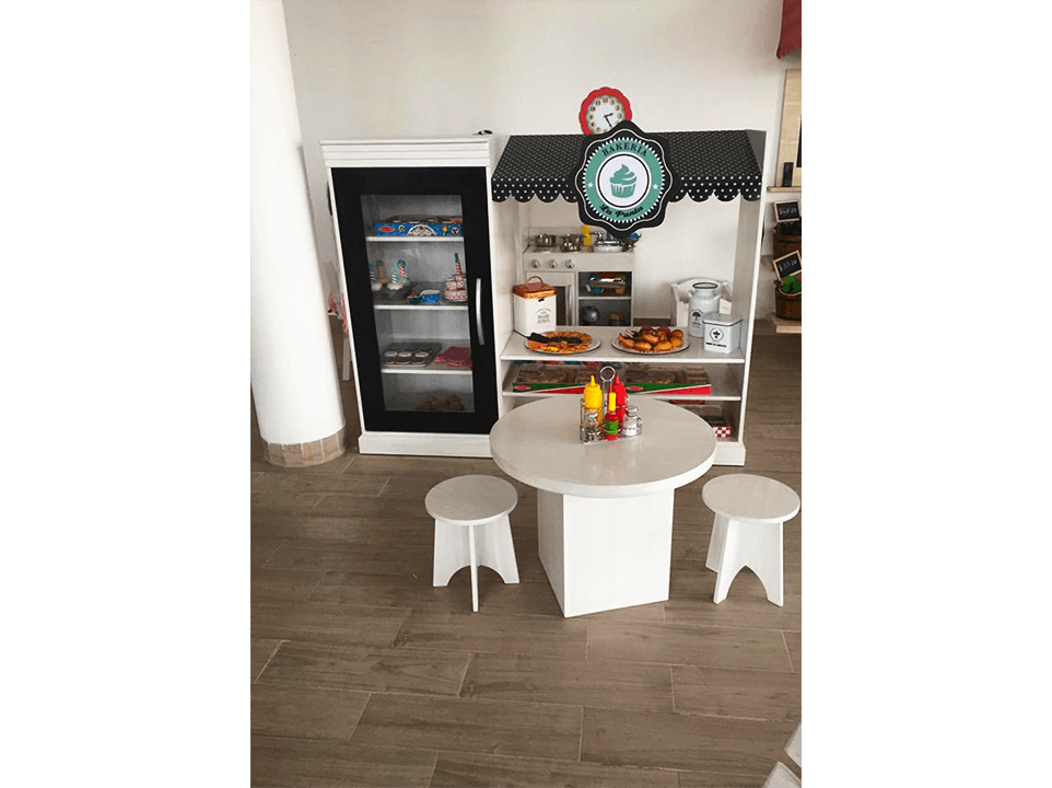 Una habitación con mesa y taburetes y nevera.
