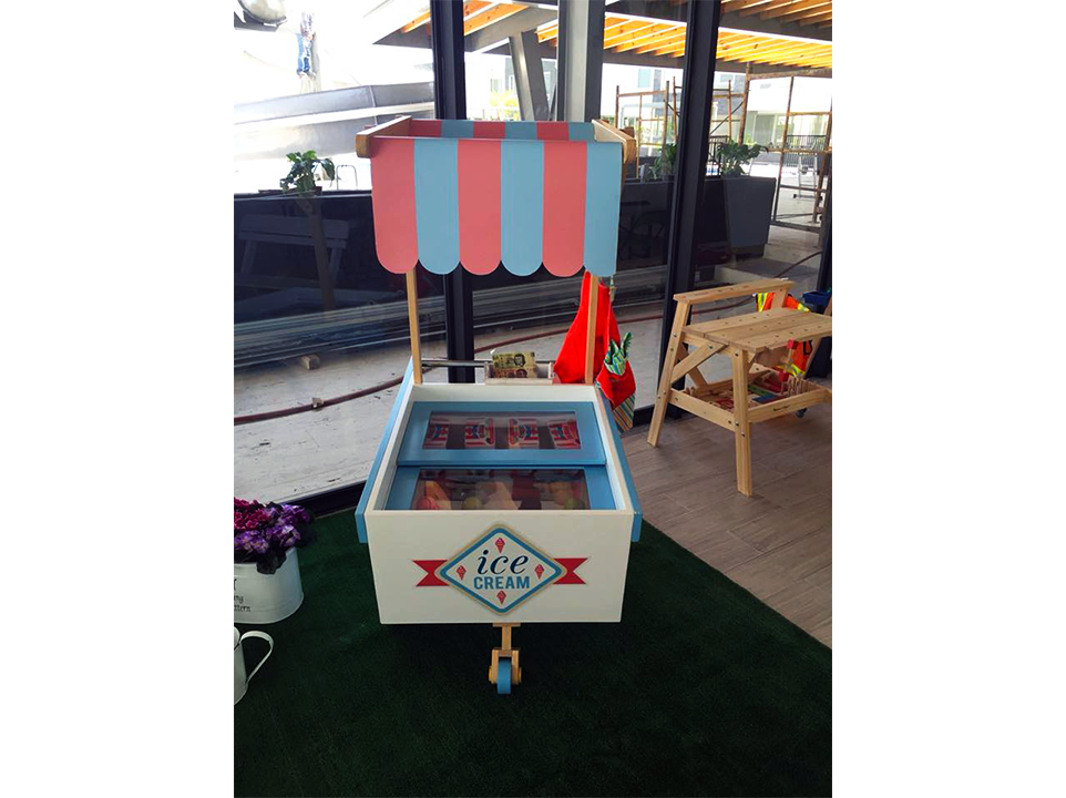 Un pequeño carrito de helados con un toldo rosa y azul
