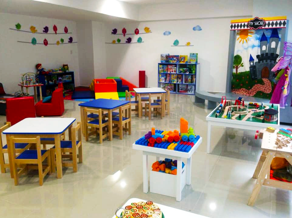 Una habitación infantil con mesas y sillas llenas de juguetes.