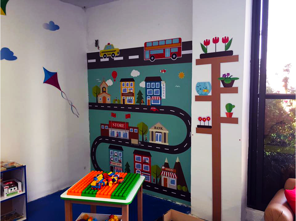 Una habitación infantil con una mesa y un mural en la pared.