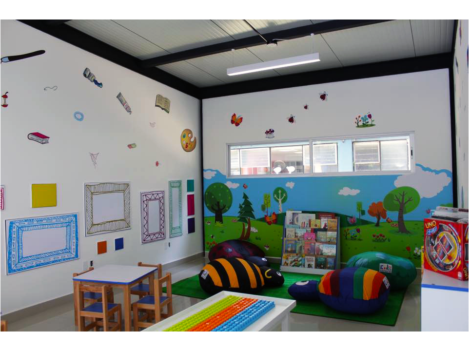 Una habitación para niños con mesas, sillas y una estantería.