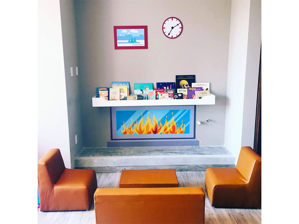 Un salón con chimenea, sillas, una mesa y un reloj en la pared.