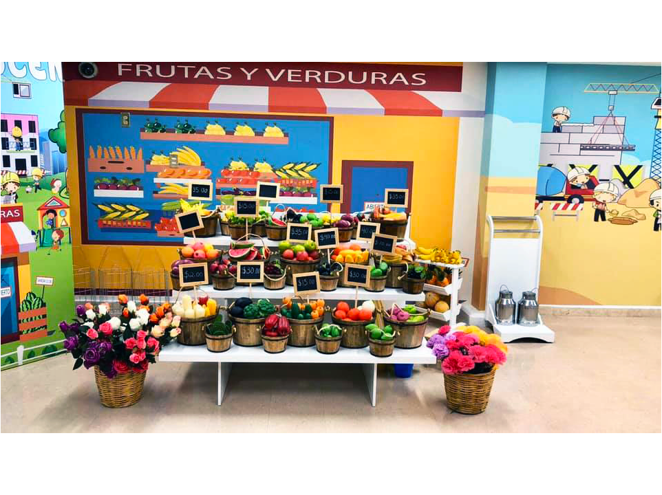 Una exhibición de frutas y verduras frente a un cartel que dice frutas y verduras