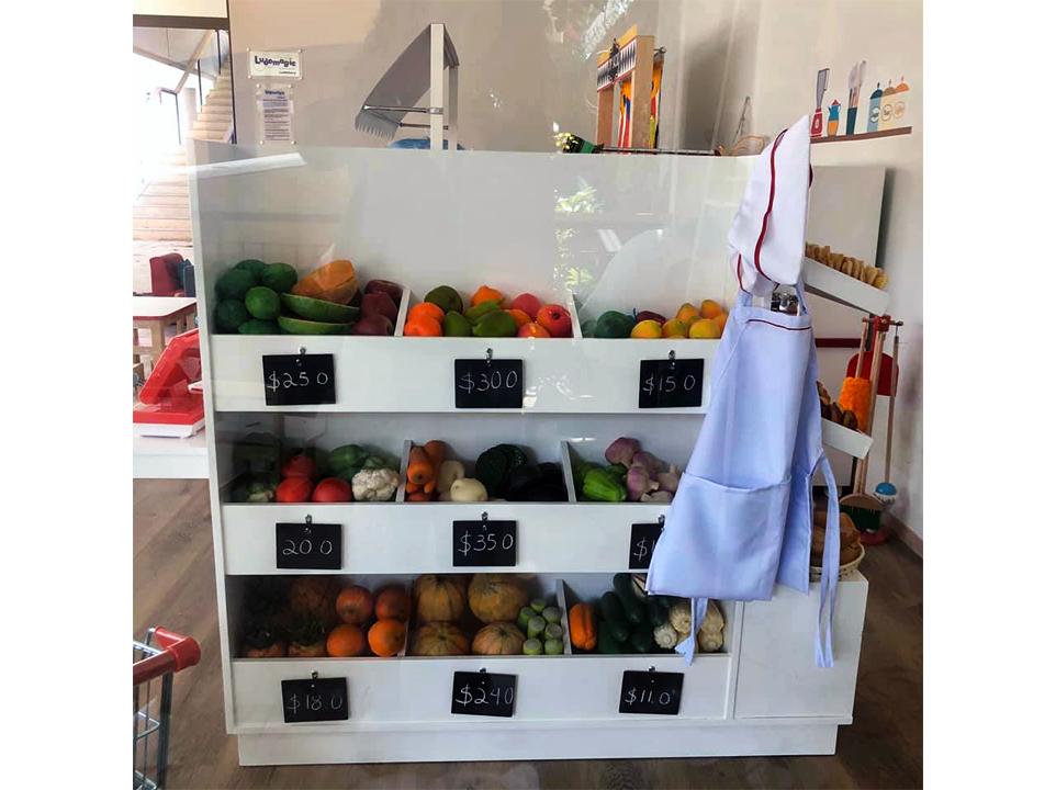 Una exhibición de frutas y verduras en una tienda con un delantal blanco colgado en la pared.