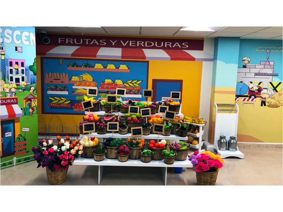 Una exhibición de frutas y verduras frente a un cartel que dice frutas y verduras