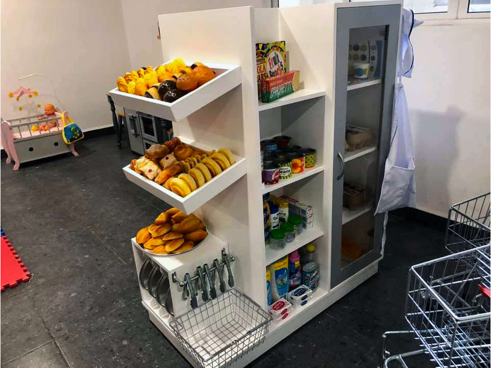 Una juguetería con refrigerador y estantes llenos de comida y bebida.