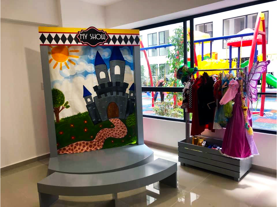 Una habitación con un cuadro de un castillo y un parque infantil al fondo.