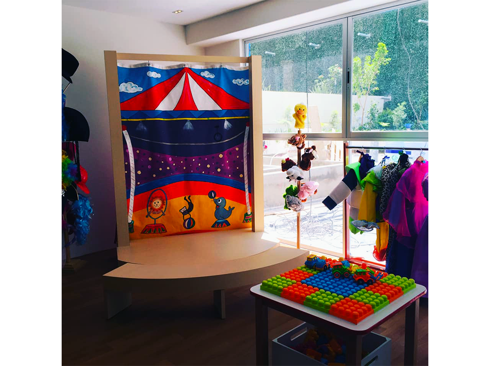 Una sala con un teatro de marionetas y una mesa con juguetes.