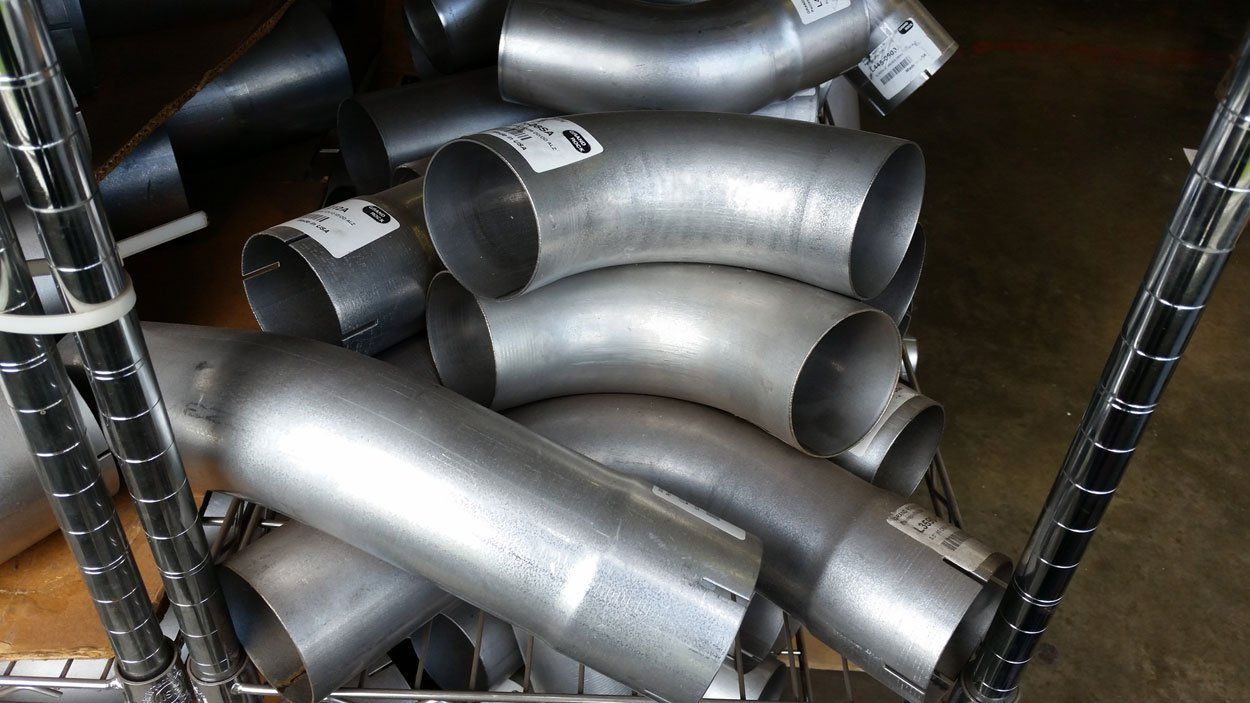A collection of steel exhaust pipes piled on top of each other