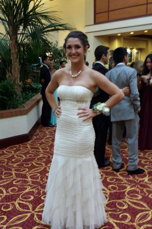 A woman in a white strapless dress is standing on a red carpet