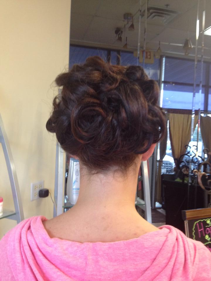 A woman in a pink shirt has her hair in a bun