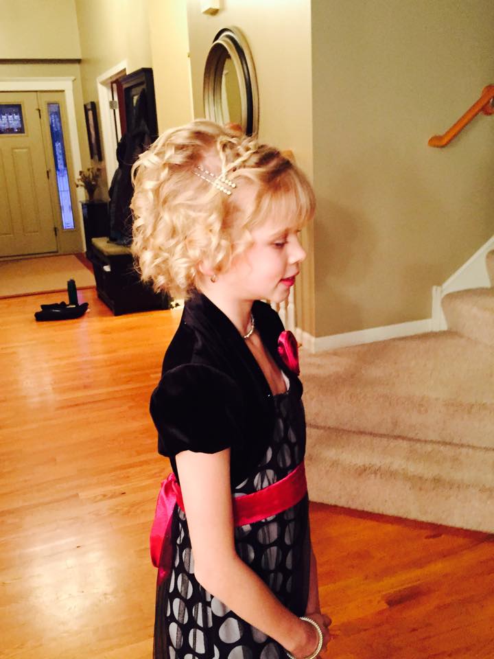 A little girl in a black and white dress is standing in a living room