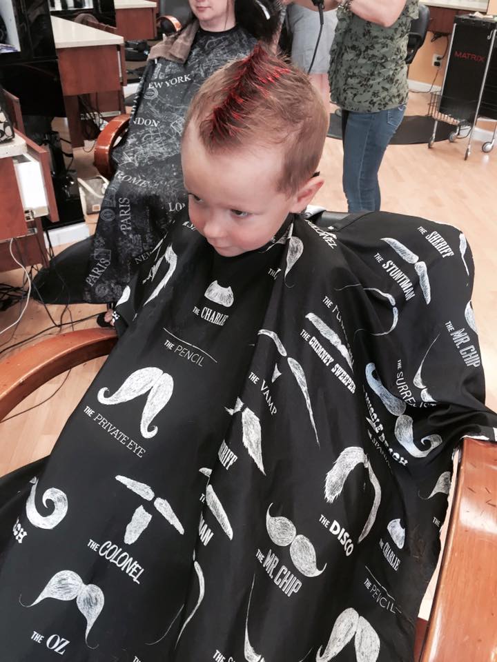 A young boy is getting his hair cut at a barber shop
