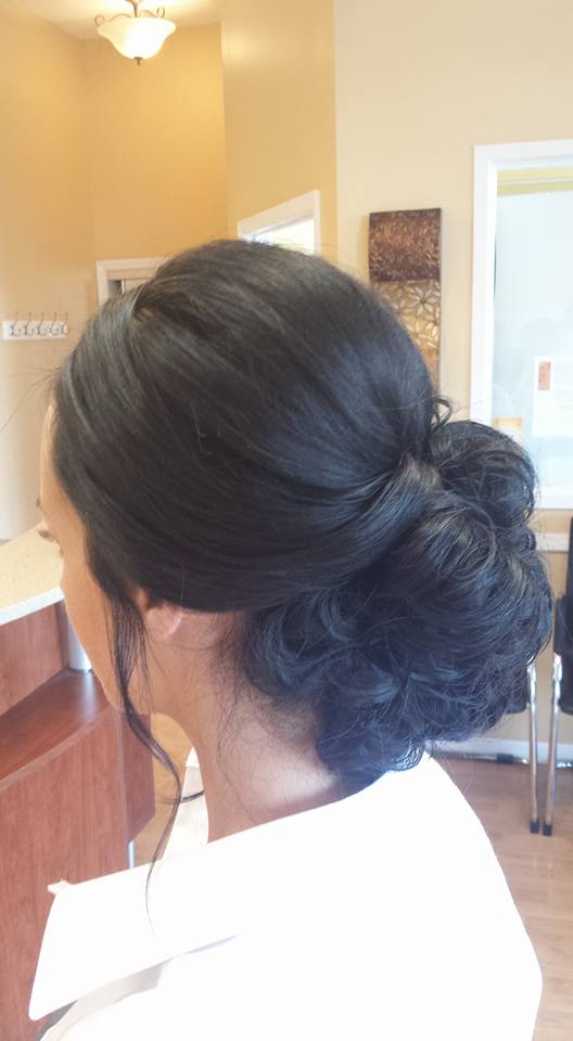 A woman is wearing her hair in a bun in a salon.