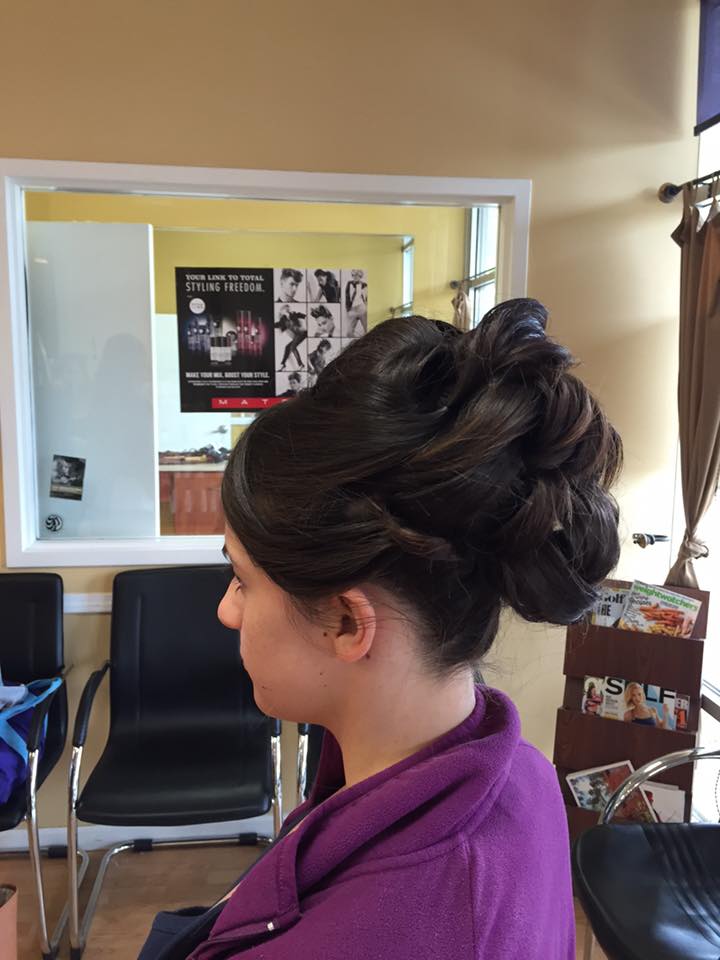 A woman is sitting in a chair with her hair in a bun.