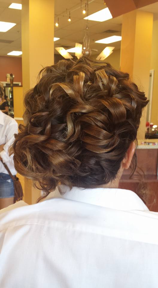 A woman with curly hair is getting her hair done in a salon.