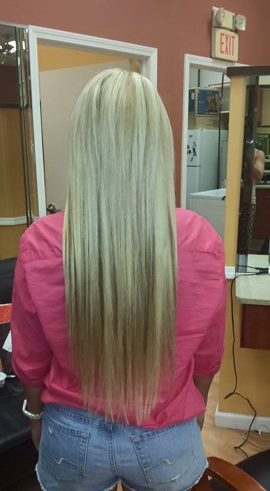 A woman with long blonde hair is standing in a salon.
