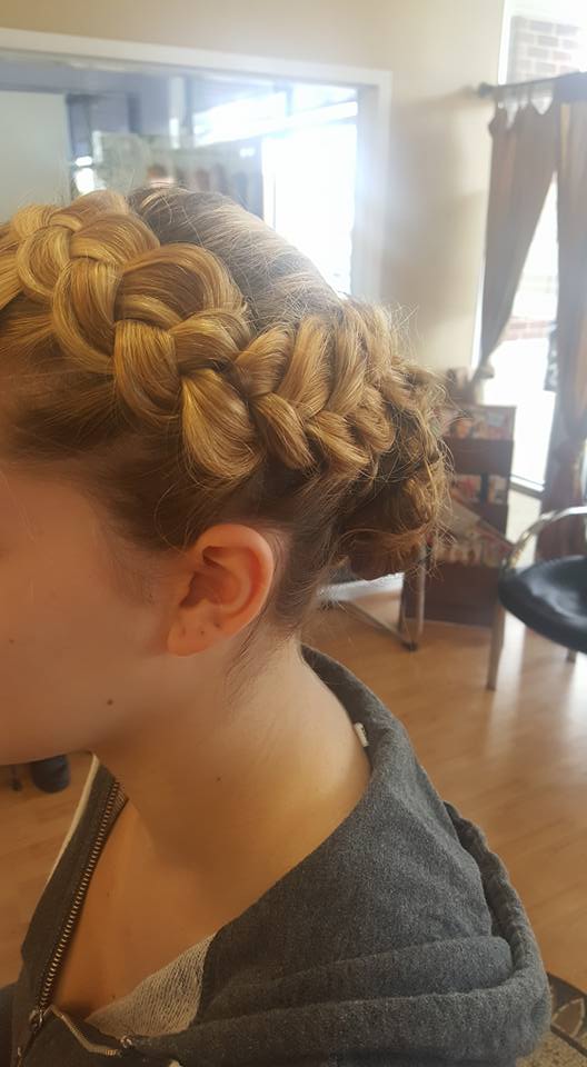 A woman is wearing a braided hairstyle in a salon.