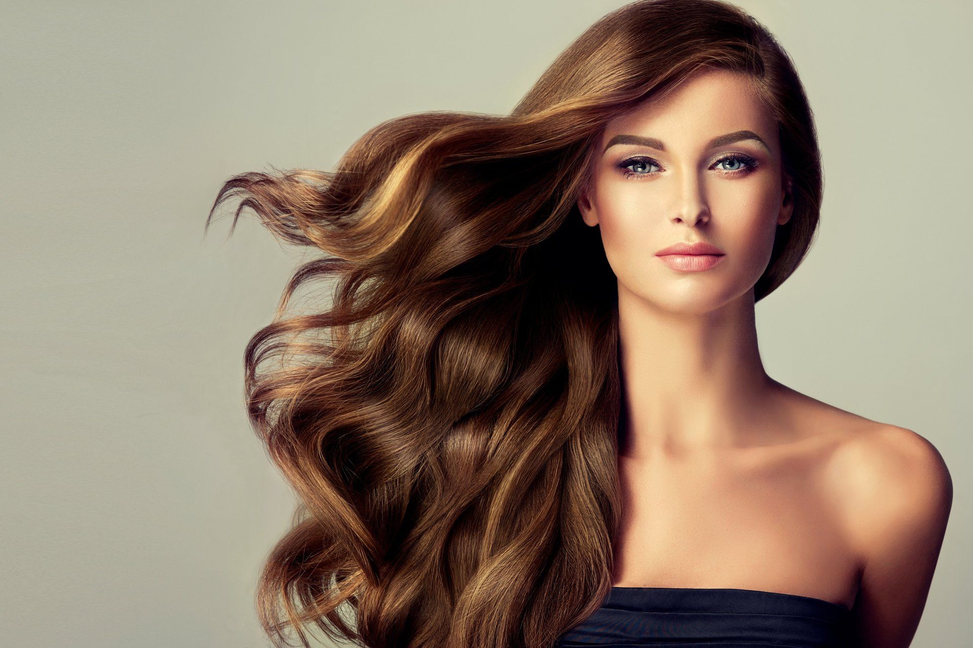 A woman with long brown hair is wearing a black strapless top.