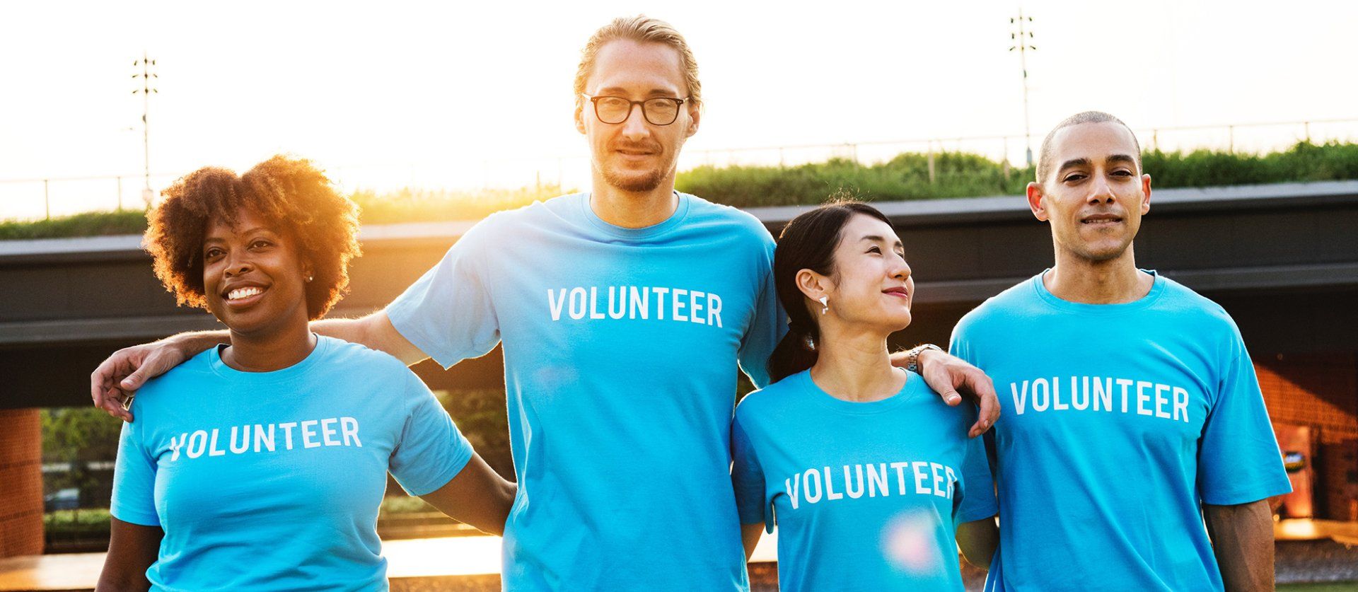 A group of people wearing blue volunteer shirts are standing next to each other.