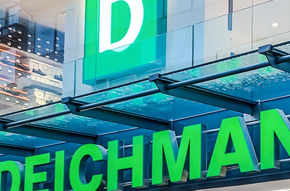 Uma placa verde brilhante da loja de calçados Deichmann, com letras grandes, instalada na fachada de um prédio.