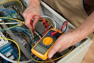 Seattle High Voltage Electric Contractor — Electrician Checking Fuse Box in Burien, WA Seattle High Voltage Electric Contractor — Electrician Checking Fuse Box in Burien, WA