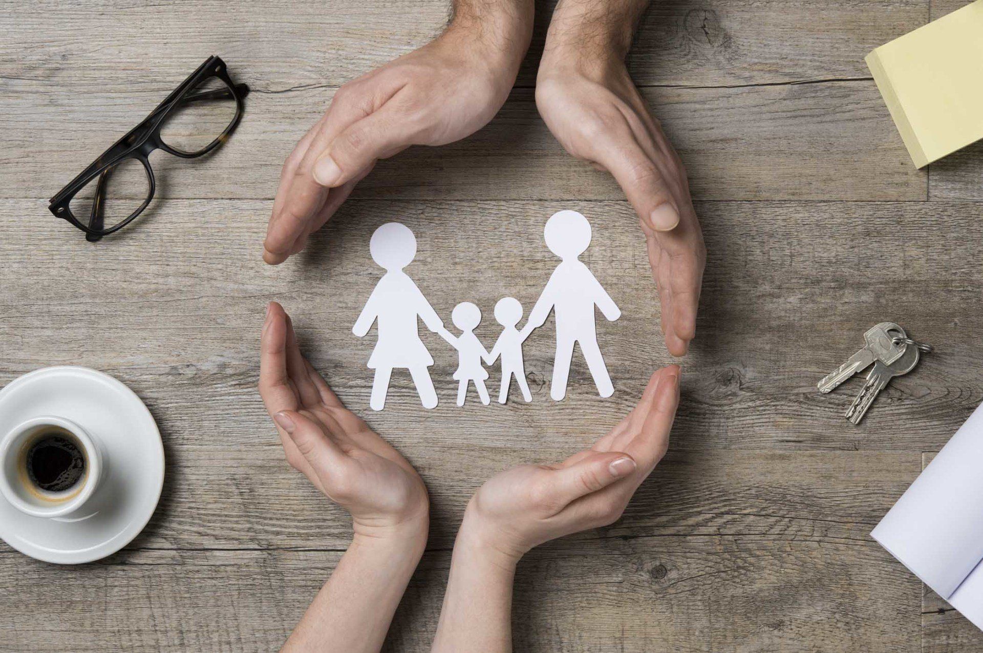 paper cut out of family circled by hands