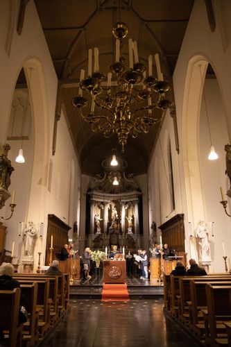 Kathedraalinterieur met kerkbanken, altaar en grote kroonluchter onder een hoog gewelfd plafond.