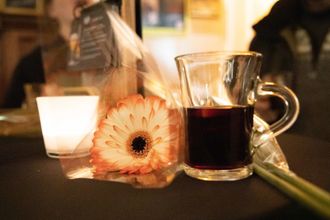 Een glazen kan en een kop sterke koffie naast een perzikbloem op een tafel.