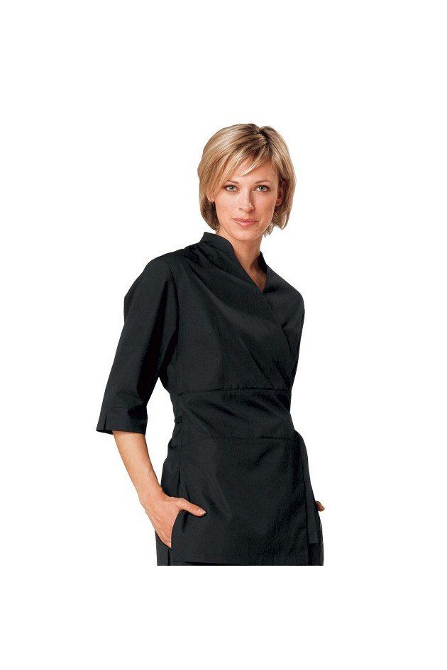 Une femme porte une chemise noire avec ses mains dans ses poches.