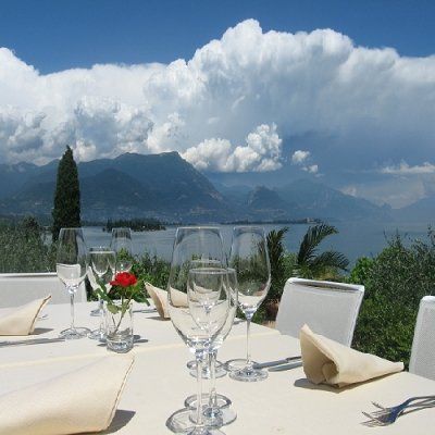 Tavolo da pranzo all'aperto con vista su un lago di montagna, immerso in un'atmosfera suggestiva tra nuvole.