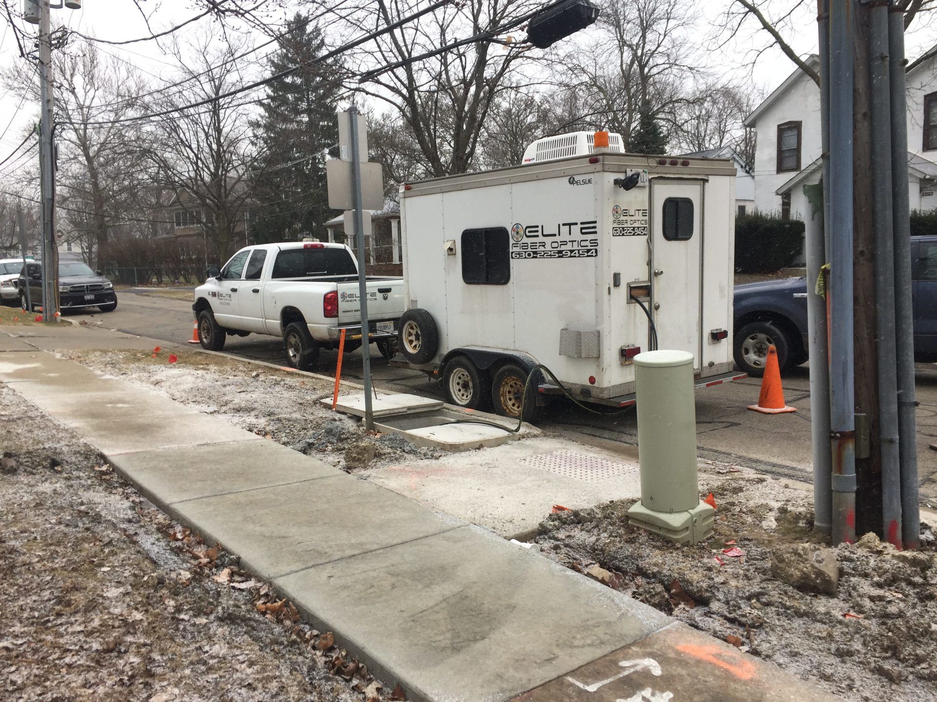 A white trailer is parked on the side of the road next to a sidewalk.