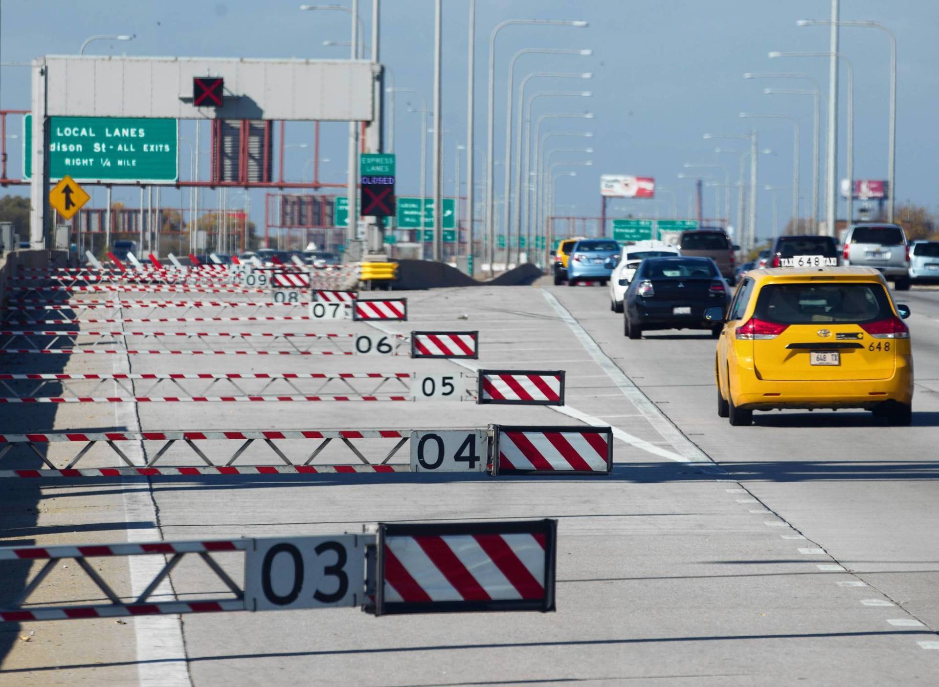 A yellow car is driving down a highway next to a sign that says 03
