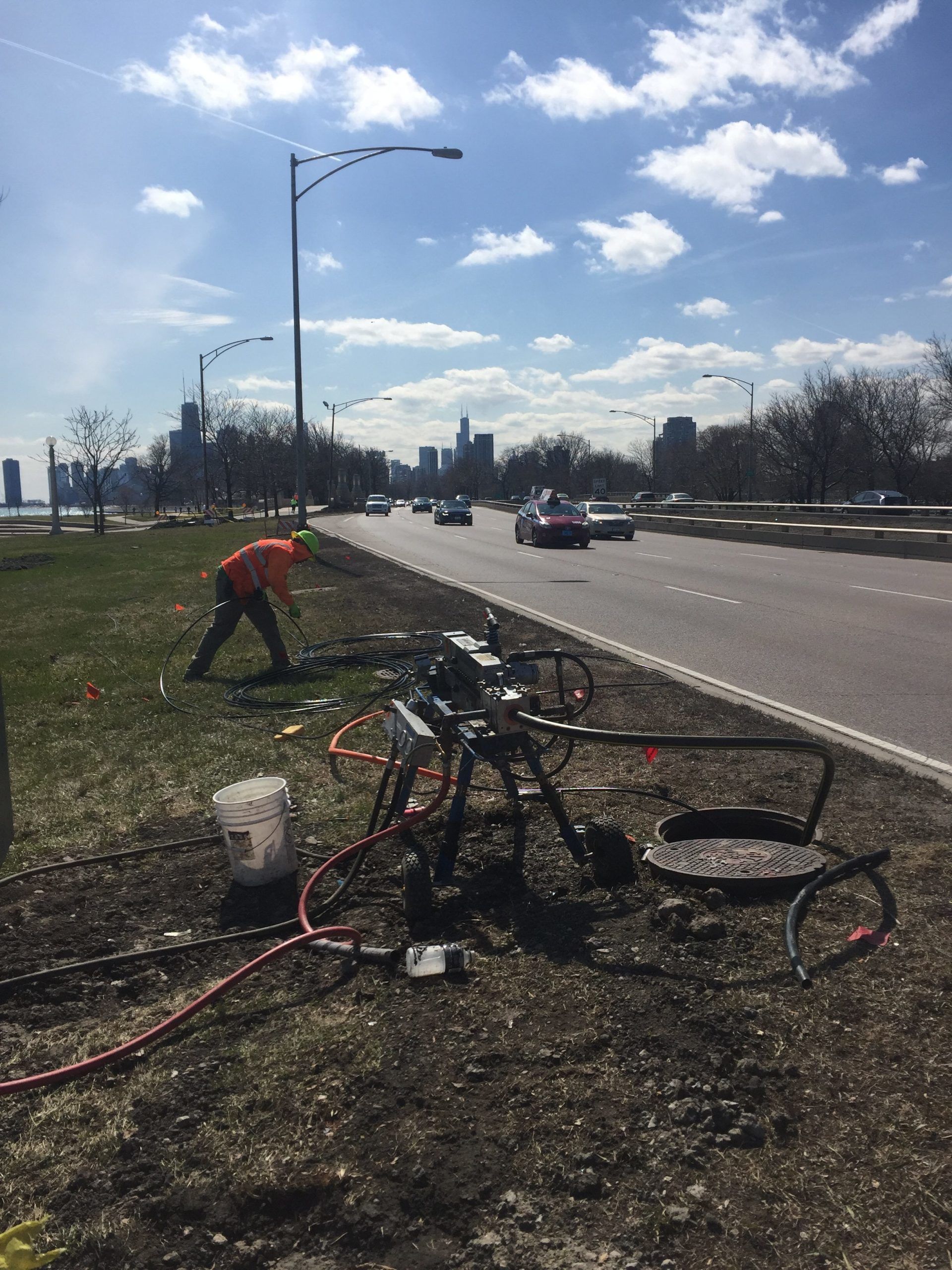 A man is working on a bench on the side of a road.
