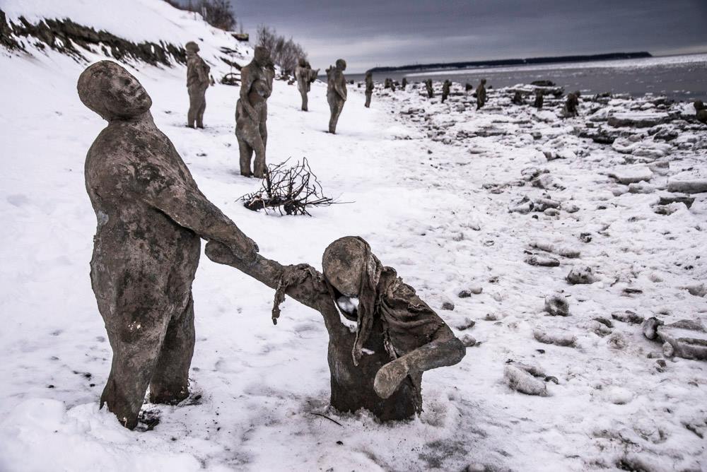 A group of statues are standing in the snow holding hands.