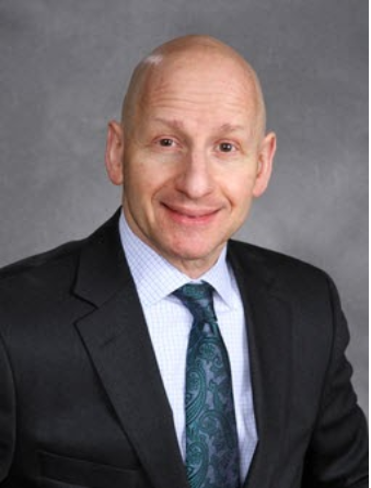 A man in a suit and tie is smiling for the camera.