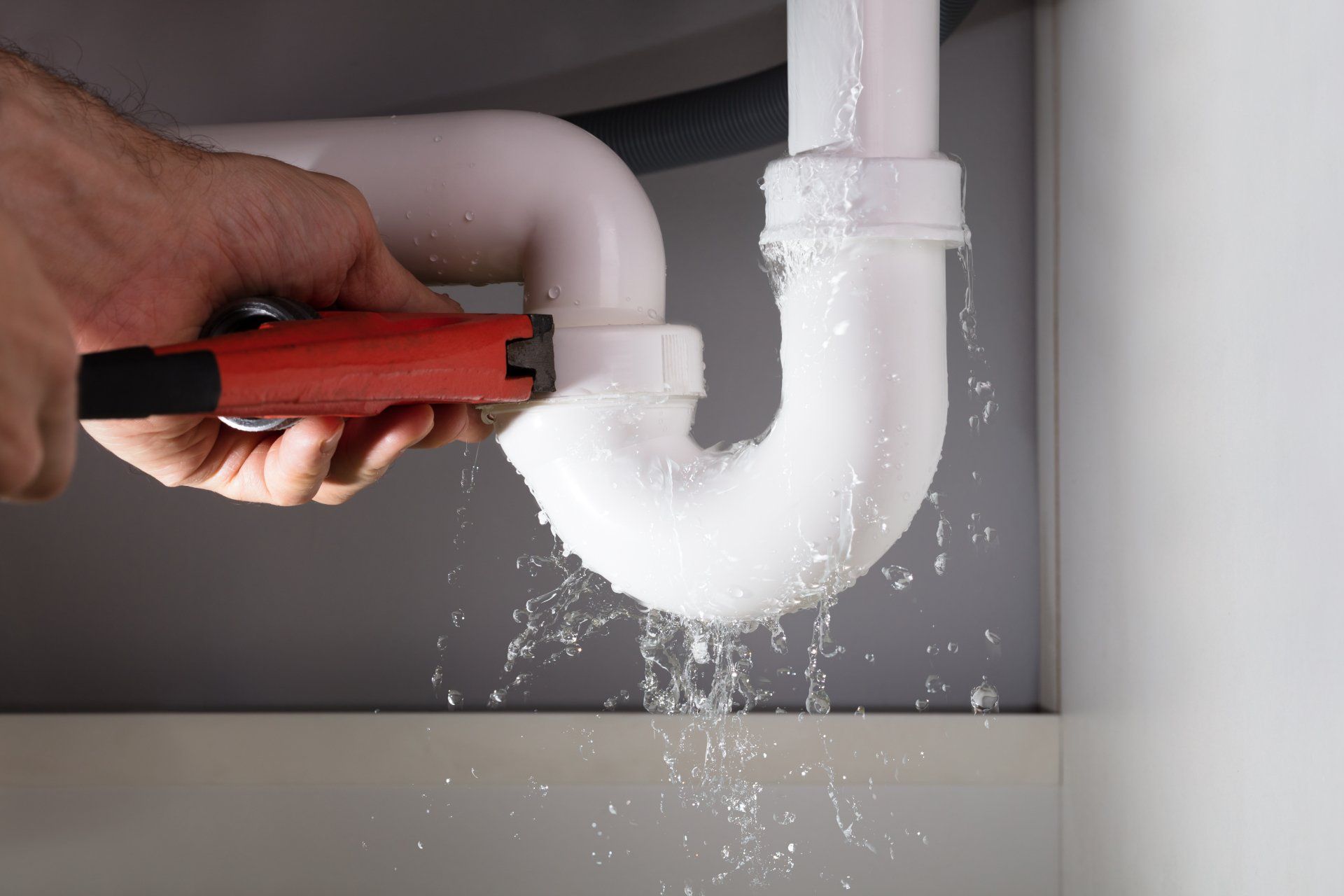 Plumber Fixing White Sink Pipe With Adjustable Wrench — Campbell’s Complete Plumbing in Tamworth, NSW
