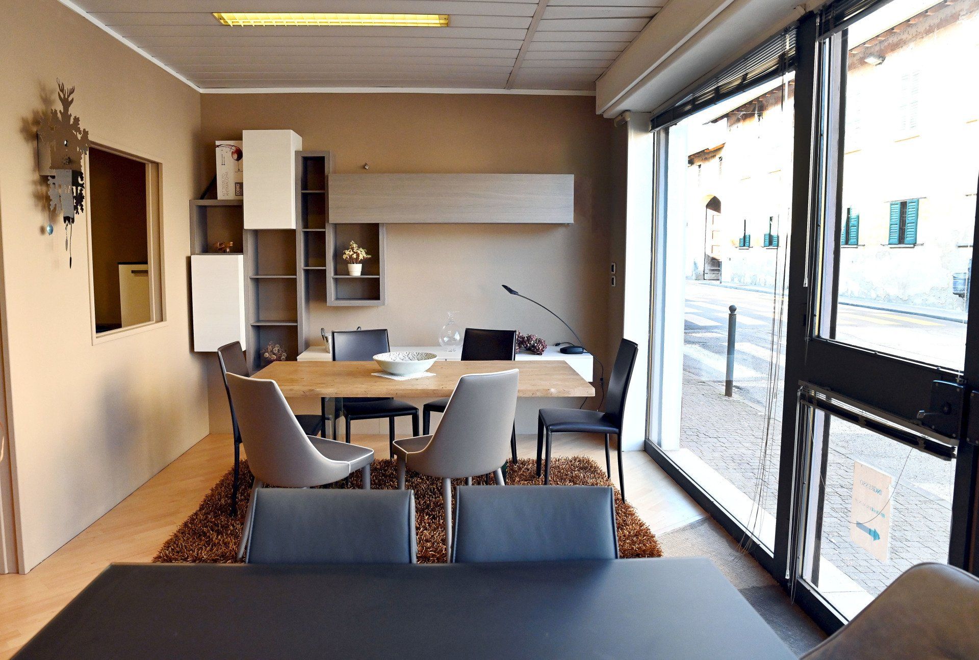Sala riunioni moderna con tavolo, sedie, scaffali e ampie finestre lungo una parete.