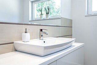 Bright space-tap - Plumbing Repair in Yorkville, IL White bathroom sink with silver faucet and soap dispenser, set against a neutral-toned tile wall