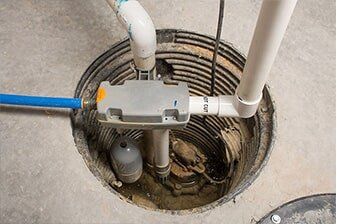 Sump Pump Repair - Plumbing Repair in Yorkville, IL Sump pump in a concrete pit, with a gray pump cover, white PVC pipes, blue pipe, and a float.