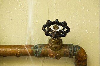 Frozen Pipe Repair - Plumbing Repair in Yorkville, IL A corroded copper pipe with a black valve is leaking water onto a beige wall.