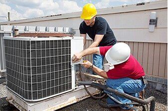 Air Conditioner Repair - Plumbing Repair in Yorkville, IL Two HVAC technicians in hard hats, repairing an air conditioning unit on a rooftop.